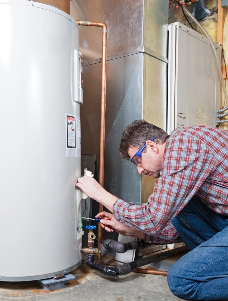 Plumber flushing a water heater in a Ventura, CA garage to remove hard-water sediment