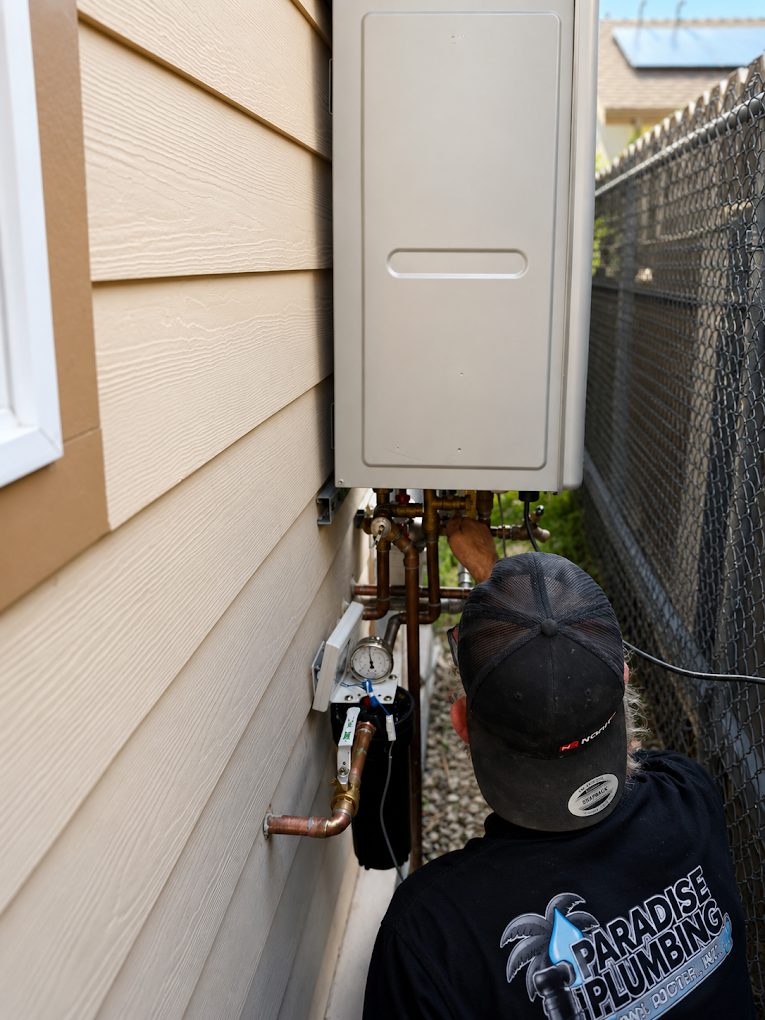 AAA Paradise Plumbing technician servicing an exterior-mounted tankless water heater in Ventura, CA