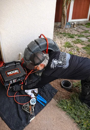 AAA Paradise Plumbing technician clearing a sewer line with a drum drain machine at an outdoor cleanout in Ventura, CA